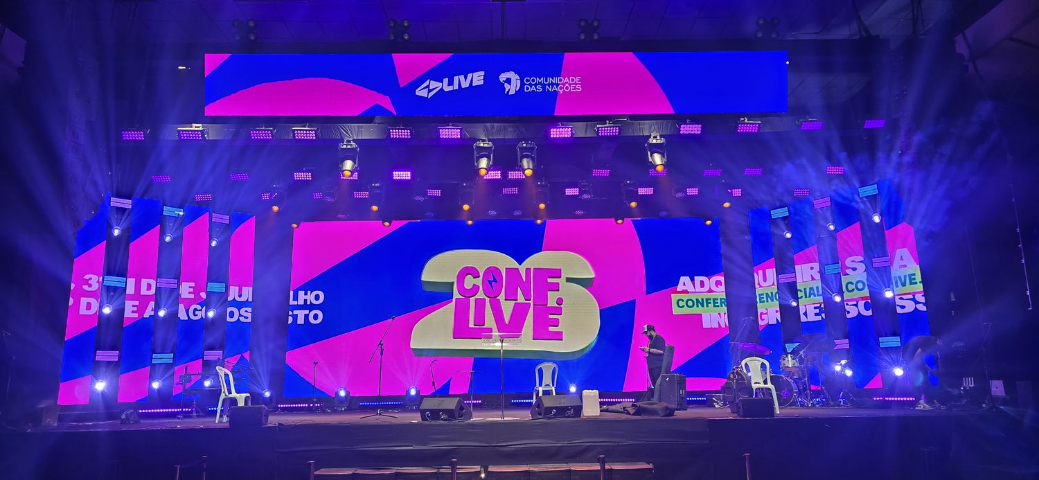 Palco da CONF.LIVE 26 com painel de LED central, painéis verticais e iluminação cênica